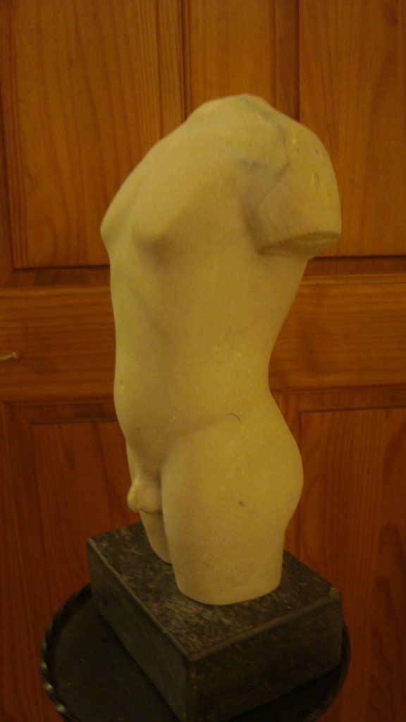 Carving of torso in white side view